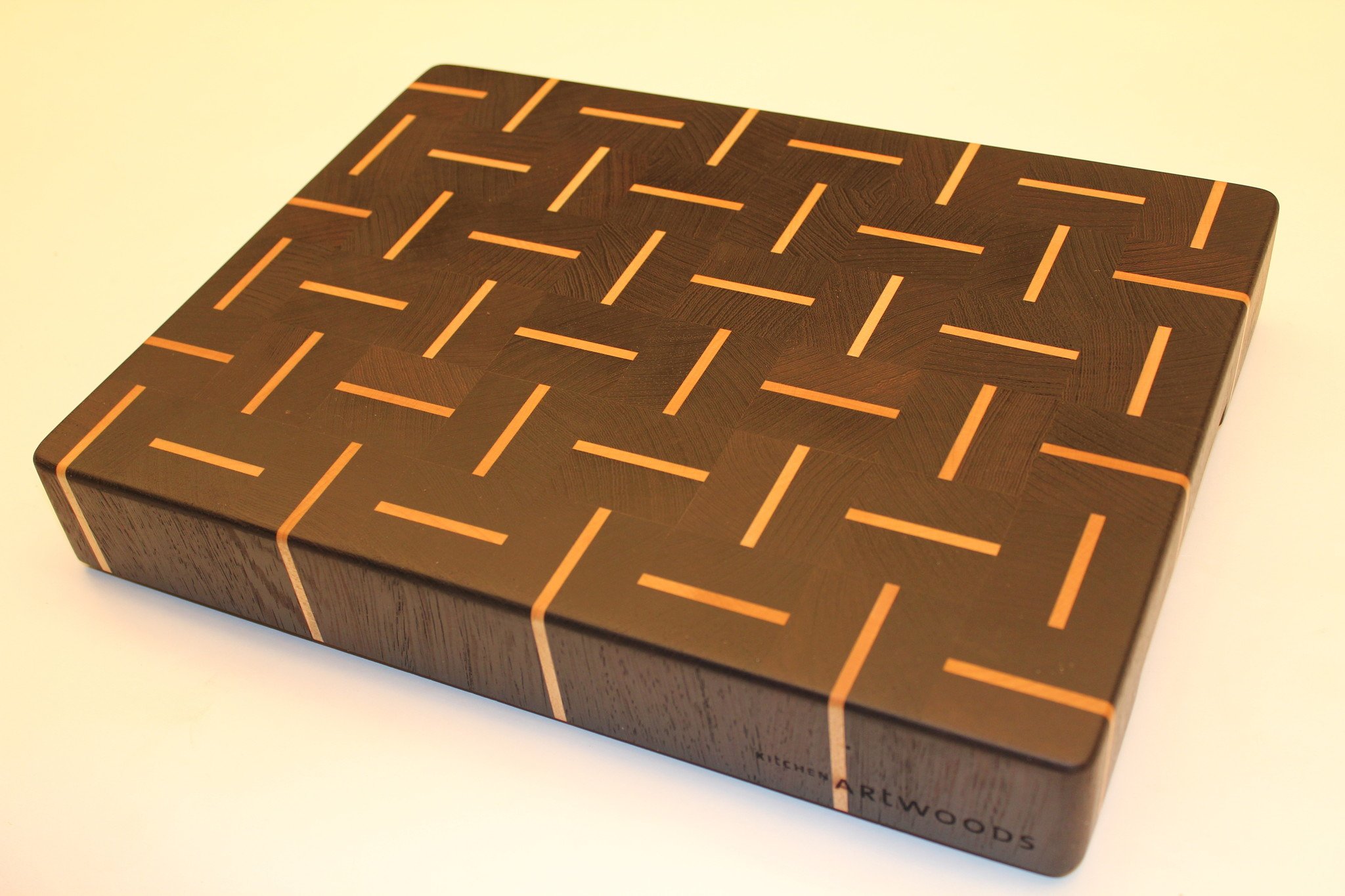 End grain cutting board of dark wenge wood with alternating stripes of hard maple