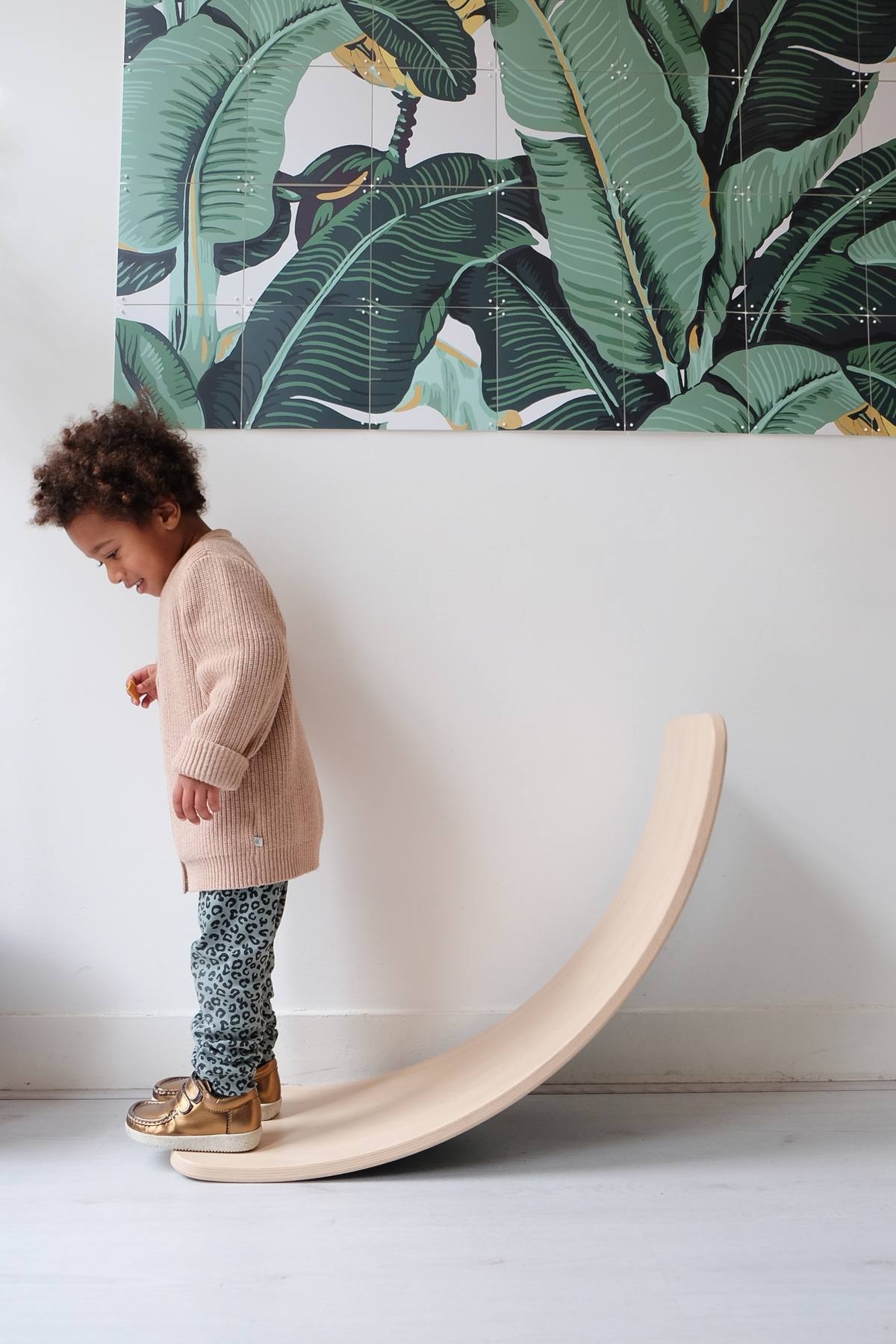 Child standing next to a natural Wobbel balance board