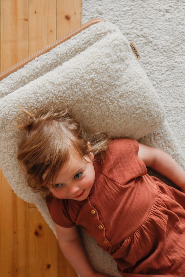 Tout-petit allongé contre une planche d’équilibre Wobbel avec un coussin doux