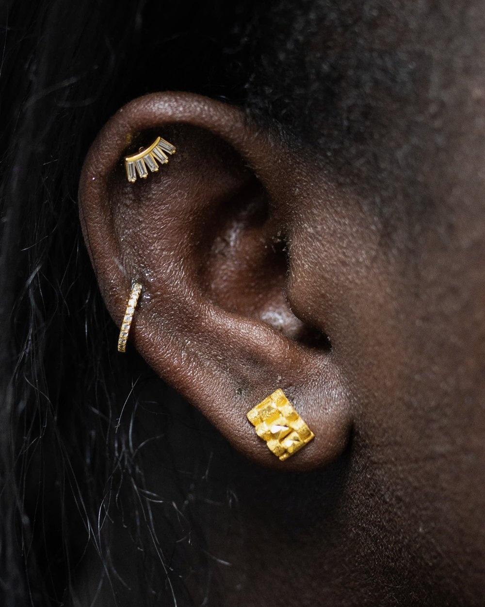 Oor met gouden piercing sieraden in helix en oorlel