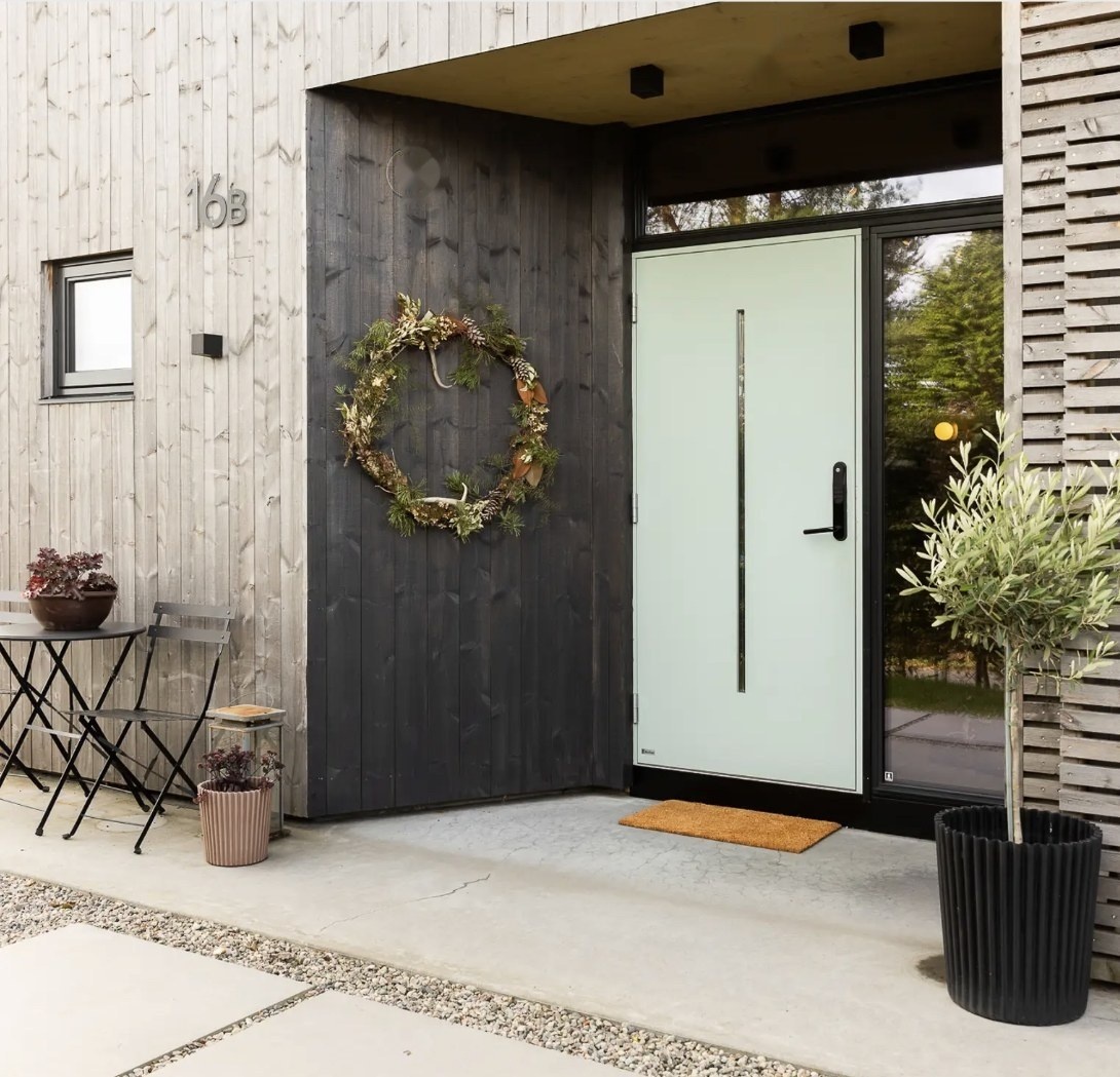 Hauseingang mit dunkler Holzfassade in Jotun Trebitt Woodcare 9811 Muted Charcoal neben heller, silbergrau verwitterter Schalung