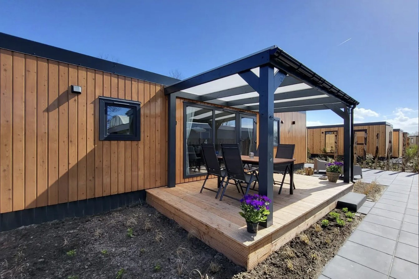 Ferienhaus mit senkrechter Lärchenschalung und Terrasse, warm goldbraun lasiert