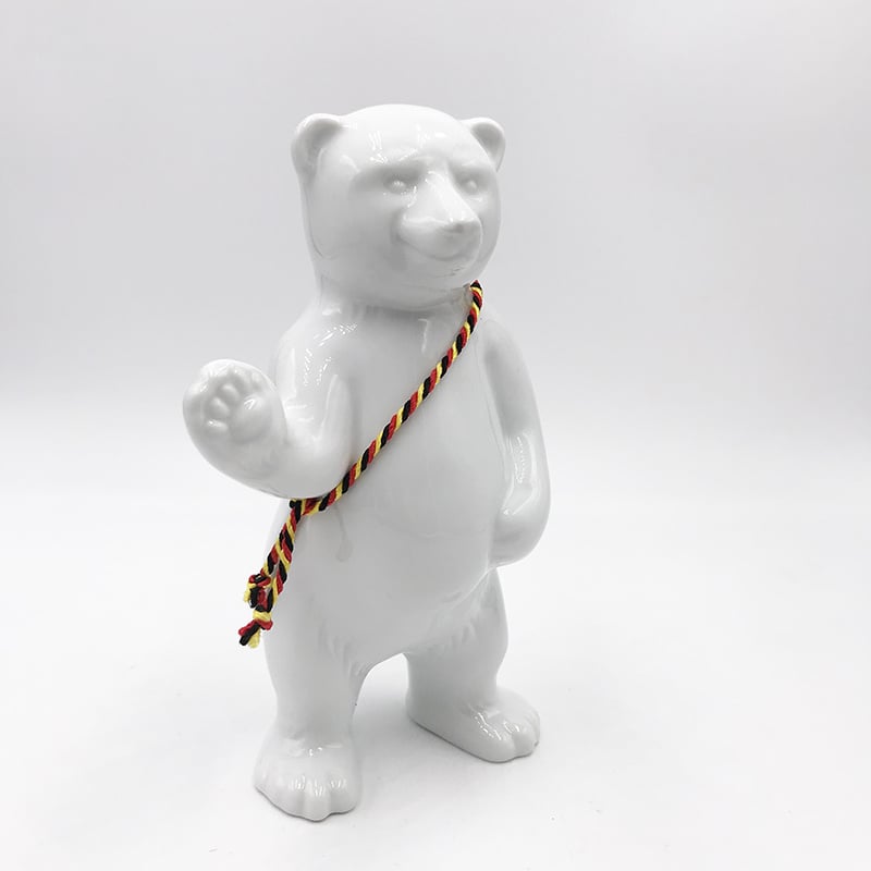 ART-DOMINO® BY SABINE WELZ Porcelain bear from Berlin - With black, red and yellow sash