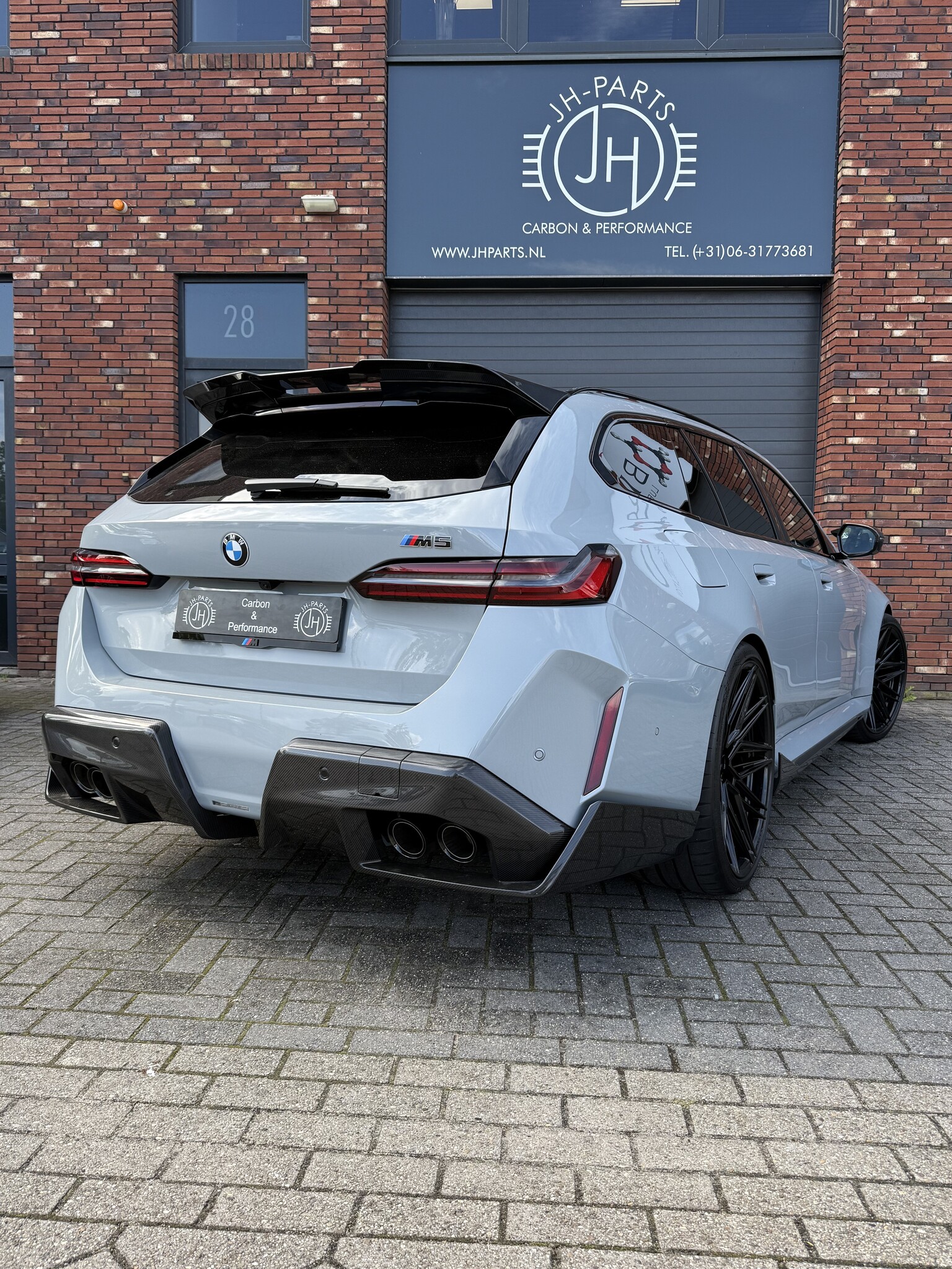 BMW G99 M5 Touring schuin van achteren met carbon diffuser, sideskirts en dakspoiler