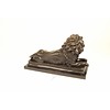 A bronze sculpture of a reclining lion (left)