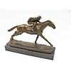 Een bronzen beeld van een racende jockey en paard