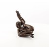 An erotic bronze sculpture of a nude female pleasing herself while lying down