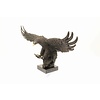 A large bronze sculpture of a descending eagle