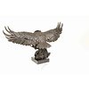 A large bronze sculpture of a descending eagle