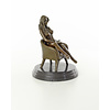 Een bronzen beeld van een vrouwelijk naakt zittend in een stoel
