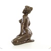 A bronze sculpture of a kneeling female nude