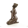 Een groot bronzen beeld van een zittende naakte dame