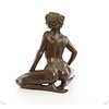 A bronze sculpture of a kneeling female nude