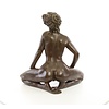 Een groot bronzen beeld van een zittende naakte dame