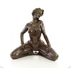 A bronze sculpture of a kneeling female nude