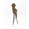 A bronze sculpture of a lady with hat seated on a barstool