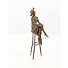 A bronze sculpture of a lady with hat seated on a barstool