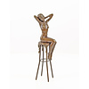 A bronze sculpture of a female nude seated on a barstool