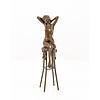 A bronze sculpture of a female nude seated on a barstool