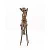 A bronze sculpture of a female nude seated on a barstool