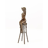 A bronze sculpture of a female nude seated on a barstool
