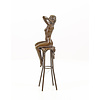 A bronze sculpture of a female nude seated on a barstool