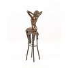 A bronze sculpture of a female nude seated on a barstool