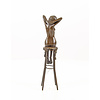 A bronze sculpture of a female nude seated on a barstool