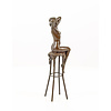 A bronze sculpture of a female nude seated on a barstool