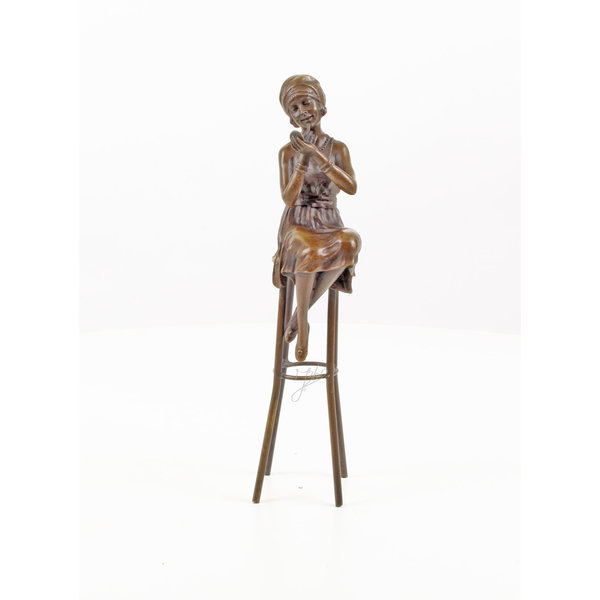  A bronze sculpture of a lady on barstool applying lipstick