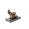 A bronze sculpture of a kneeling female nude