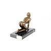 A bronze sculpture of a kneeling female nude