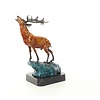 A bronze sculpture of a roaring stag on a rock