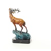 A bronze sculpture of a roaring stag on a rock