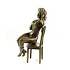 A bronze sculpture of an enticing female seated on a chair