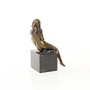 A bronze sculpture of a sitting female nude