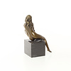 Een bronzen beeld van een zittende naakte dame