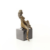 Een bronzen beeld van een zittende naakte dame