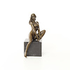 A bronze sculpture of a sitting female nude