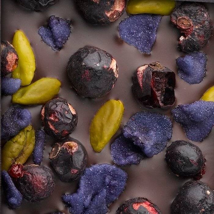 - B2B ENTRÉE | SYRAH II | Valrhona dunkle Schokolade 70% mit Pistazien aus Bronte, kandierte Veilchen und gefriergetrocknete Schwarze Johannisbeere, 110g