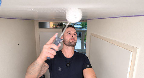 Plafond in volledige banen verven met een roller en telescoopsteel
