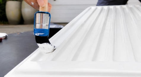 Inkepingen en randen van een radiator schilderen met een ronde kwast