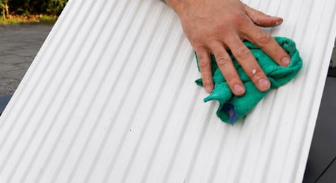 Geschuurde radiator stofvrij maken met een stoffer en microvezeldoek