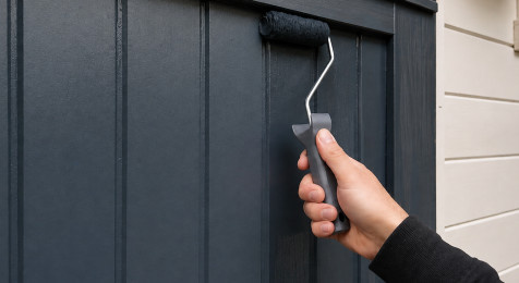 Dekkende beits aanbrengen op een houten schuurdeur met kwast en roller
