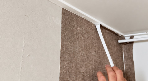 Behang strak afsnijden bij plafond en plint met spatel en scherp mes