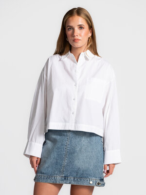 Blouse Astha. Cropped elegance. Deze witte, boxy blouse combineert tijdloze eenvoud met een moderne twist. De korte lengt...