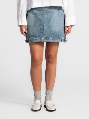 Skirt Mara. Legs for days. This short denim skirt plays with proportions thanks to the playful button detail at the hem. ...