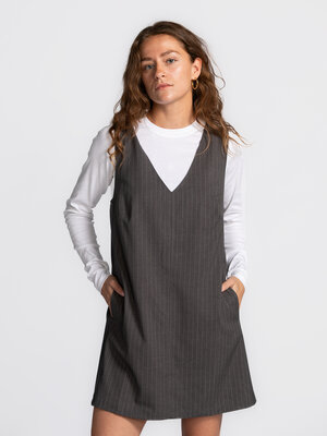 Robe Mel à fines rayures. Layer up with style. Cette robe salopette grise à fines rayures allie charme intemporel et touc...