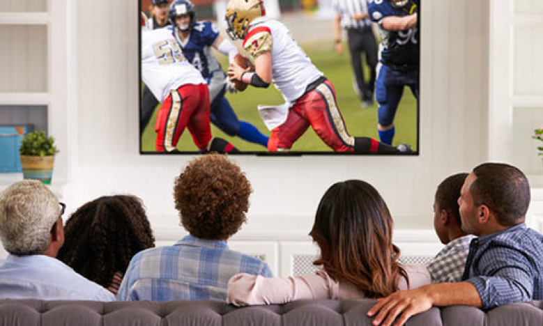 Group of people gathering round to watch a sports game