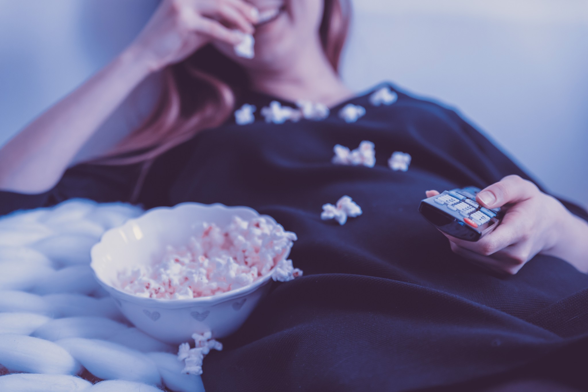 a person watching tv with popcorn